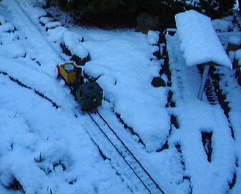 LGB-Lok Stainz mit zum Schneepflug umgebauten Feldbahn-Kastenwagen bei ersten Schneerumversuchen im frischen Neuschnee