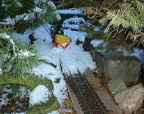 LGB-Lok Stainz mit zum Schneepflug umgebauten Feldbahn-Kastenwagen bei ersten Schneerumversuchen im frischen Neuschnee